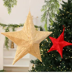 Close-up of gold sequined hanging star Christmas decoration with tree background