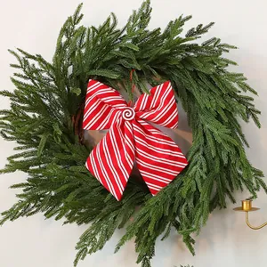 Mooie groene kunstmatige kerstkrans versierd met een rood-wit gestreepte strik