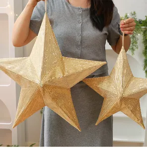 A person holding large and medium gold sequined folding stars for size comparison purposes