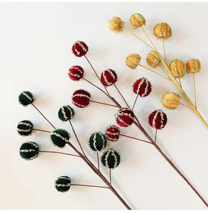 Dettaglio di rami con bacche di Natale floccate verdi, rosse e oro con glitter argento
