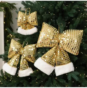 Dettaglio di fiocchi di Natale dorati a specchio appesi a un albero di Natale verde