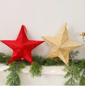 Large red and gold sequined folding star ornaments displayed on festive pine garland