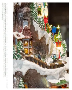 Detailed view of a lit Christmas snow village house and mountain scene ornament.