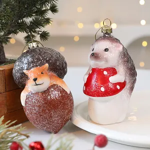 Handgemaakte glazen kerstversieringen van vossen en egels met feestelijke glitters.