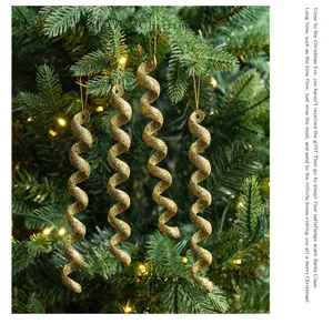 Detalle de cuatro adornos de Navidad en espiral dorada brillante en un árbol festivo.