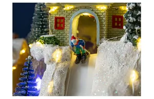 Close-up of miniature skiing figure on a snowy Christmas mountain house with LED lights