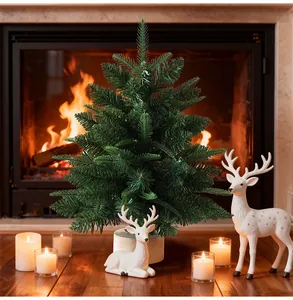 Albero di Natale da tavolo artificiale denso davanti a un camino acceso caldo