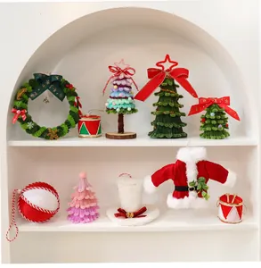 Dettaglio di mini alberi di Natale, ghirlanda e vestito di Babbo Natale in ciniglia.