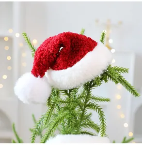 Detail van een pluchen rood-witte kerstmuts ornament hangend aan de kerstboomtakken