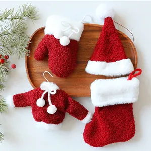 Set van pluche kerstornamenten met trui, muts, want en kerstsok op een houten dienblad