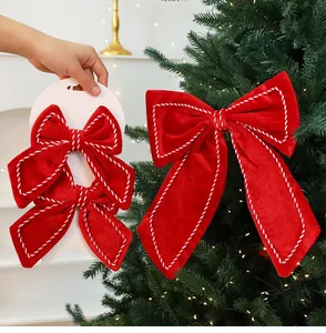 Detailed close-up of red velvet Christmas bows with white stitching on a festive tree
