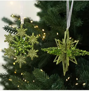 Nahaufnahme von grün glitzernden Schneeflocken- und Stern-Weihnachtsanhängern am Baum.