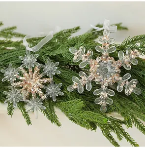 Detailansicht von transparenten Acryl-Schneeflocken mit roségoldenen Pailletten auf Tanne
