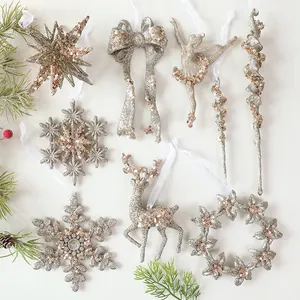 Detailansicht von champagnerfarbenem glitzerndem Weihnachtsschmuck mit Schneeflocken und Rentier.