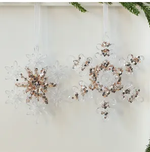 Nahaufnahme von klaren Acryl-Schneeflocken mit glitzernden Gold- und Roségold-Pailletten