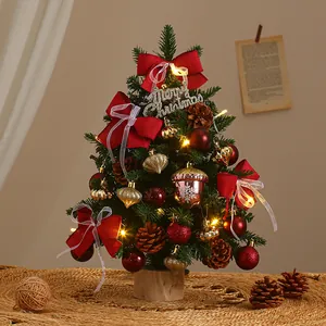 Mini DIY desktop Christmas tree decoration with red bows and warm LED lights on a wooden base