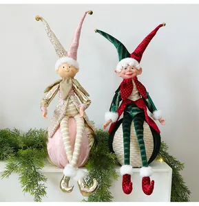 Zwei dekorative Weihnachts-Elfenpuppen auf Weihnachtskugeln mit Tannenzweigen.