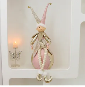Nahaufnahme einer rosa-goldenen Weihnachts-Elfenpuppe auf einer goldenen Kugel