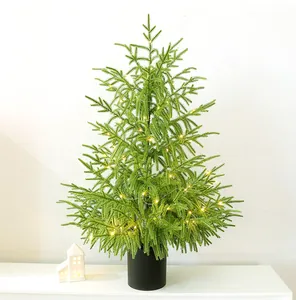 Détail d'un sapin de Norfolk artificiel avec des lumières LED chaleureuses dans un pot noir