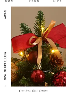 Close-up detail of a mini desktop Christmas tree with warm LED lights and red ribbons