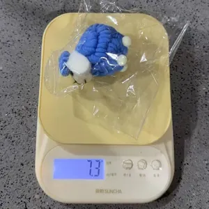 Detail view of a handmade blue felt sheep ornament being weighed on a precision scale.