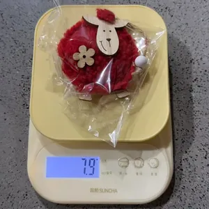 Adorno de oveja de fieltro de lana roja de 7,9 g en una balanza digital amarilla