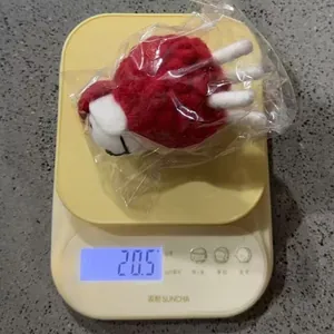 Detail view of a handmade felt sheep ornament being weighed on a yellow digital scale