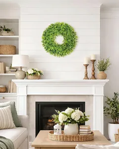Realistic artificial boxwood wreath hung above a white fireplace mantel in a cozy home