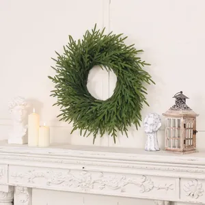 Couronne de Noël en pin Norfolk suspendue sur un manteau de cheminée blanc