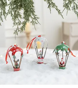 Dettaglio di tre ornamenti natalizi in metallo a forma di paracadute con Babbo Natale e un renne