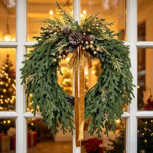 Couronne de Noël artificielle en pin avec pommes de pin, baies et ruban de velours.