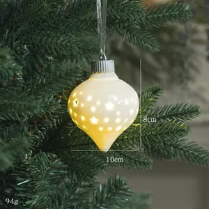Detalle de adorno navideño de cerámica luminosa en forma de gota con estrellas caladas