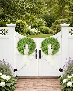 Double artificial boxwood wreaths with ribbons displayed on a white garden gate.