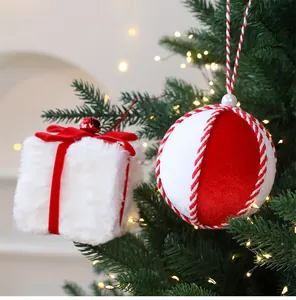 Vista detallada de bola de Navidad de peluche roja y blanca y caja de regalo en árbol.