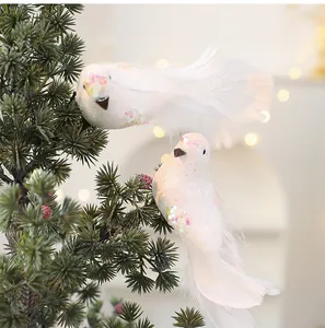 Glinsterende witte kunstmatige vogels met veren op een kerstboomtak geplaatst