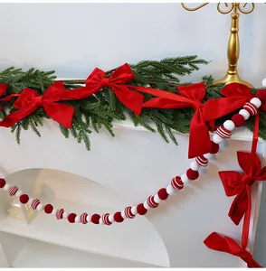 Red velvet Christmas bows and festive beaded garland on white mantle