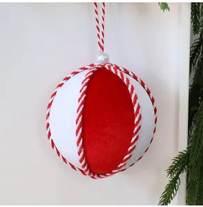Primer plano de una bola de Navidad de terciopelo rojo y blanco de 10 cm con cuerda trenzada