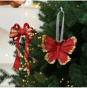Detail view of red glitter bow and butterfly Christmas ornaments on a festive tree