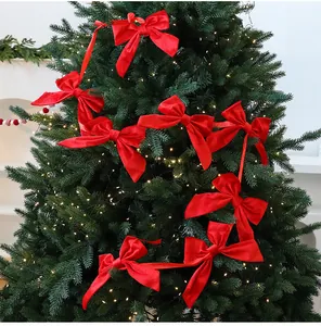 Detailed view of vibrant red velvet bow garland hanging on a lit Christmas tree