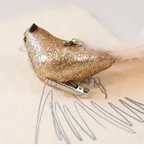 Gedetailleerde macro-opname van een gouden glitter kunstvogel met witte verenstaart