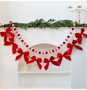 Festive red bow garland and pom-pom ball string for Christmas fireplace decoration.