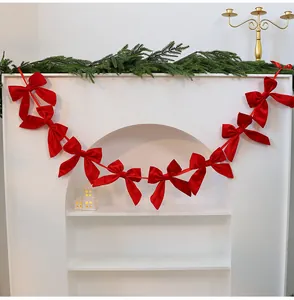 Vibrant red velvet bow garland Christmas decoration hanging on a white fireplace mantel