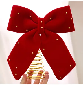 Primo piano del fiocco per albero di Natale in velluto bordeaux con accenti dorati.