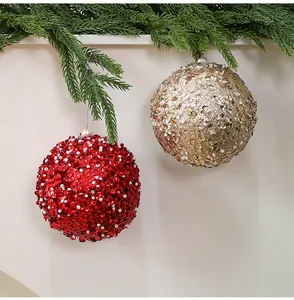 Gros plan de boules de Noël rouges et dorées de 10 cm avec perles et paillettes sur pin.