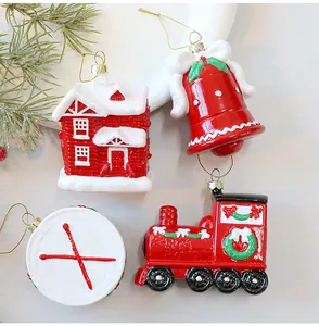 Detail van vier feestelijke rood-witte kerstboomversieringen inclusief een bel en trein.
