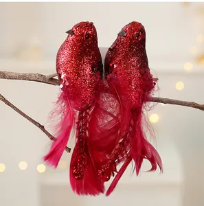 Detailopname van glitterrode kunstmatige vogelornamenten met veren op een boomtak