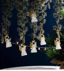 Transparente Weihnachtsengel aus Kristallglas mit goldenen Flügeln an Kiefernzweigen hängend