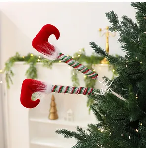 Whimsical striped Christmas elf legs decoration inserted into a lush green pine tree