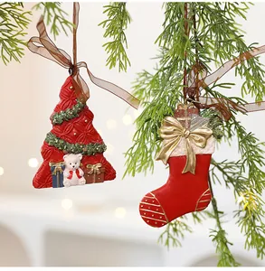 Detailed view of resin Christmas tree and stocking ornaments hanging on pine branch