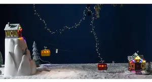 Illuminated Christmas miniature landscape scene with moving yellow and red cable cars.